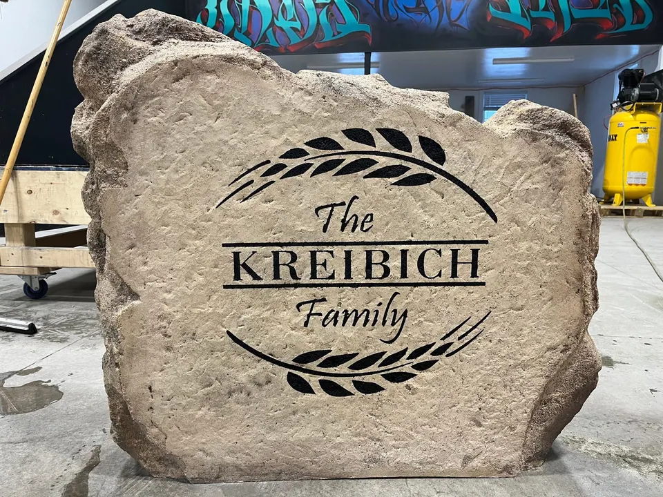 Tan family-name boulder with a wheat wreath design, finished in our shop