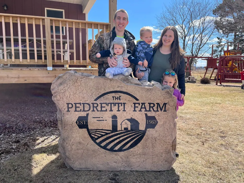 A family standing behind their large engraved farm boulder