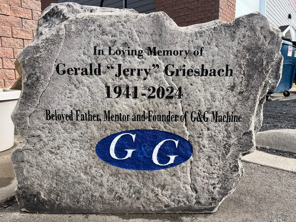 Grey memorial boulder with engraved tribute lettering and a full-color company logo