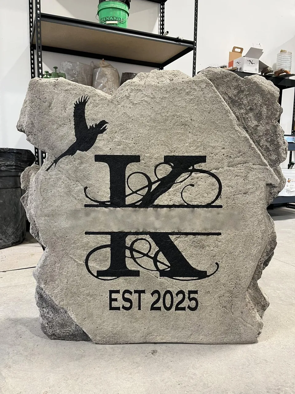 Grey boulder with a family monogram, bird artwork and established date