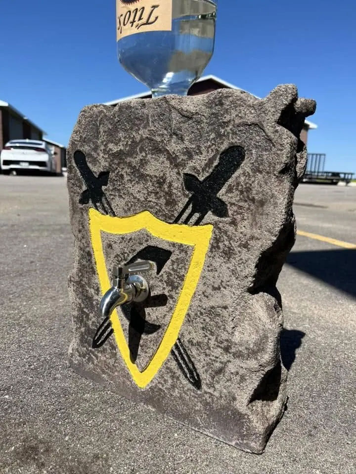 Upright grey boulder with a full-color yellow and black shield logo