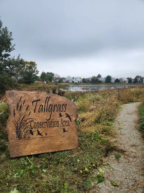 Engraved conservation area boulder beside a walking path and pond in an HOA neighborhood