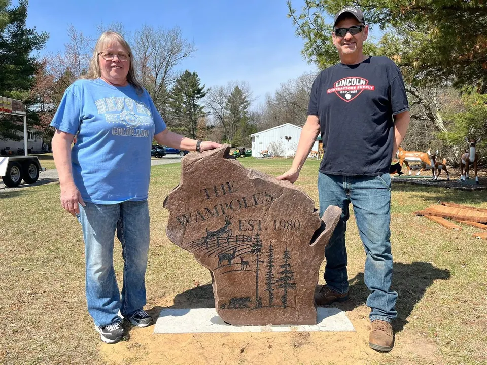 Couple standing beside a custom Wisconsin-shaped boulder